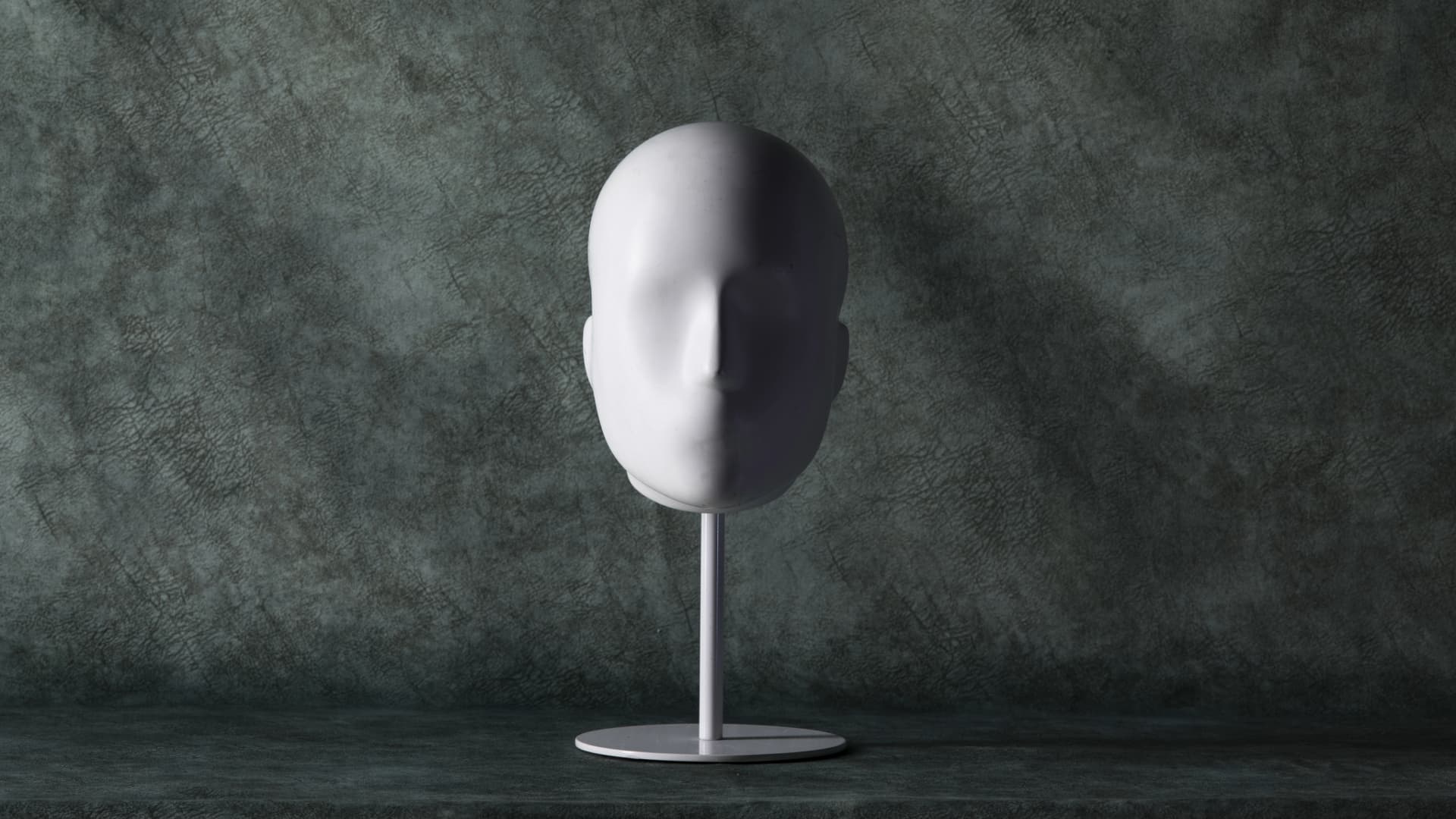 A white sculpture shaped like a head, facing forward, symbolizing introspection and expression through minimalist art.