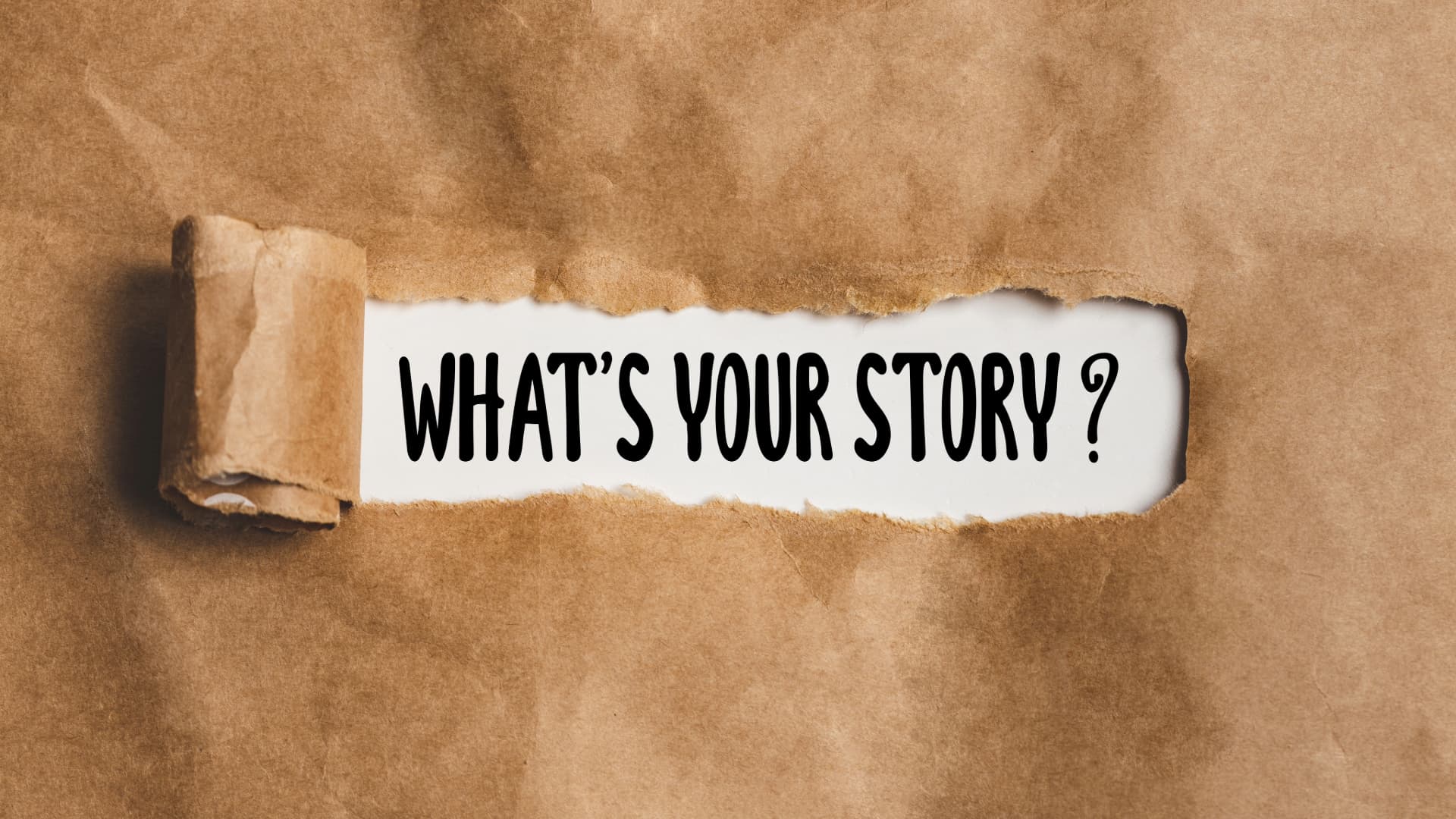 Paper with the words 'What's your story?' written on it, covered by cardboard, symbolizing the connection between art and personal identity through storytelling and self-expression.