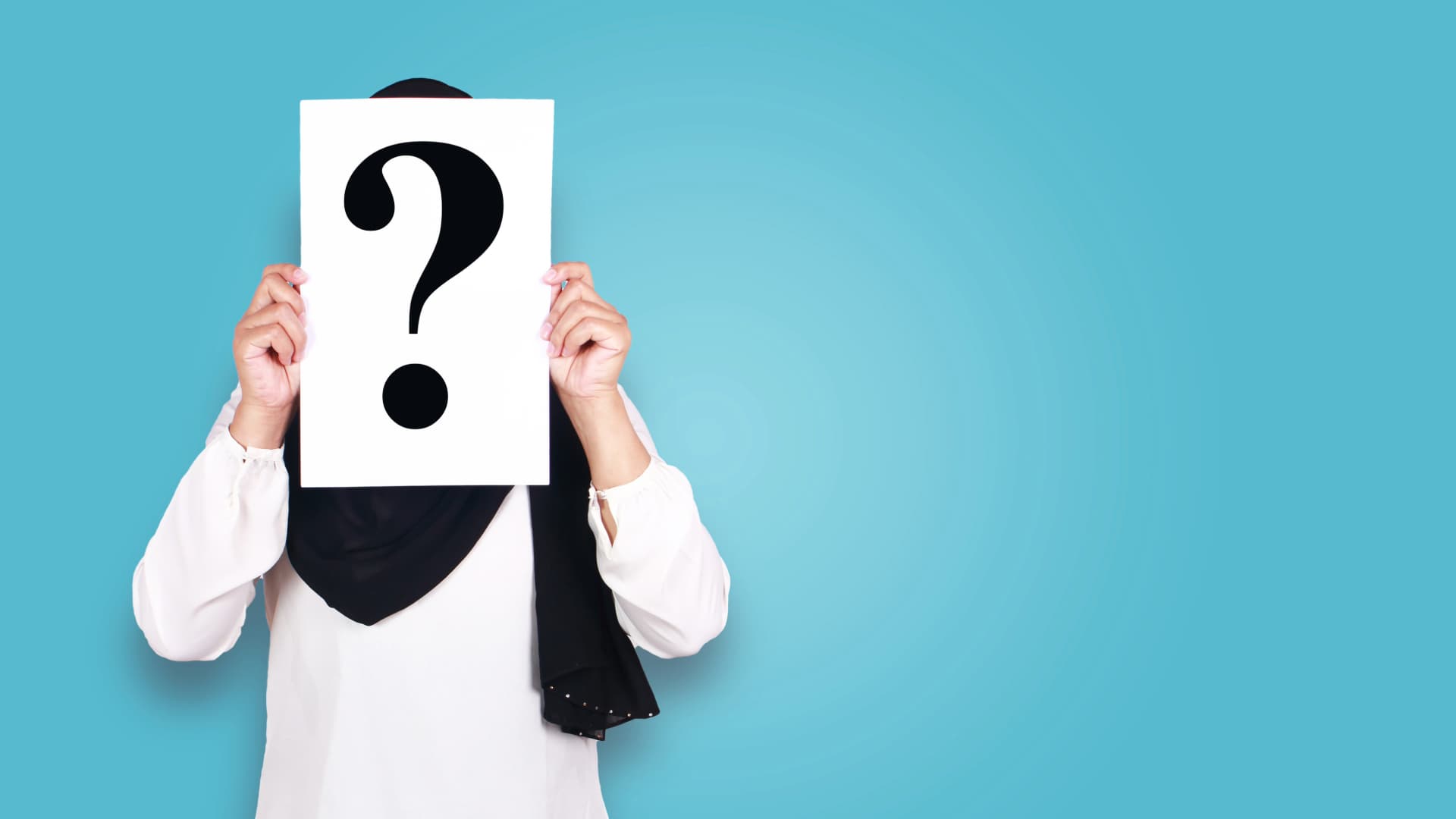A person holding a piece of paper with a question mark covering their face, symbolizing the exploration of personal identity and self-expression.